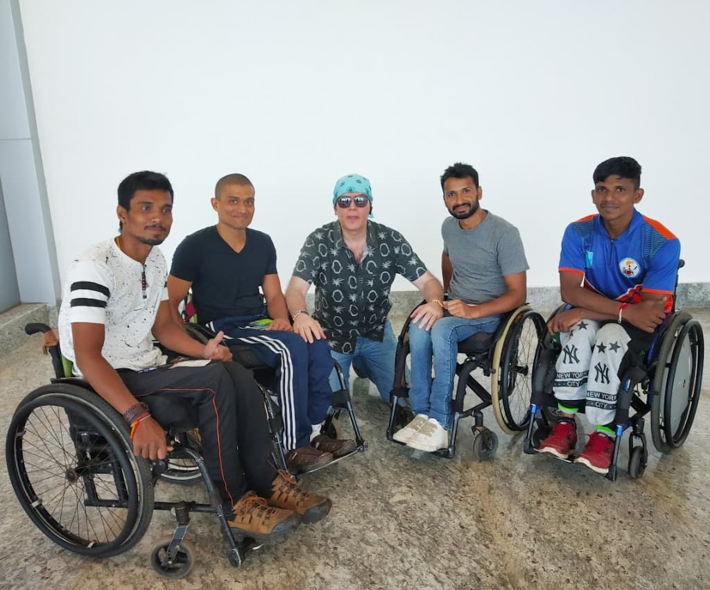 Group of wheelchair friends and athletes sitting together on the floor smiling