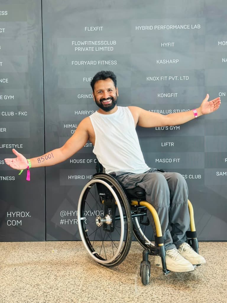 Mohammad Imran smiling proudly in his wheelchair with arms open at HYROX Delhi, showing Bib #85001