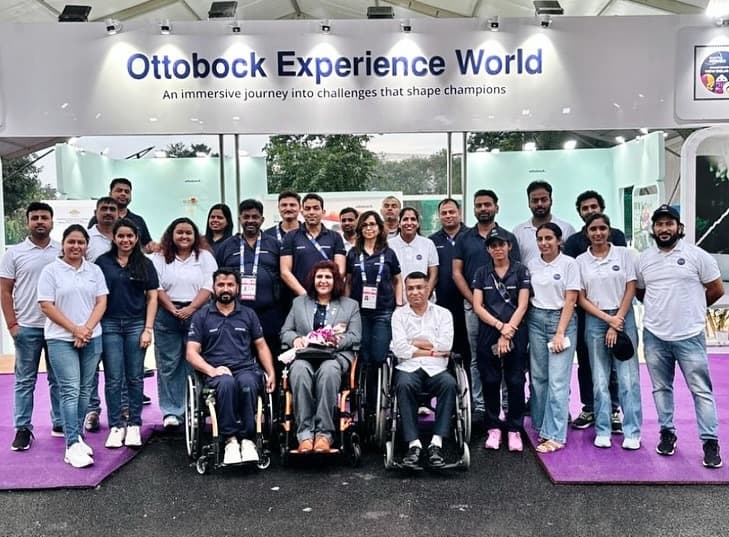 Large group photo under the Ottobock Experience World banner featuring Mohammad Imran, wheelchair athletes, and the complete event team on purple carpet
