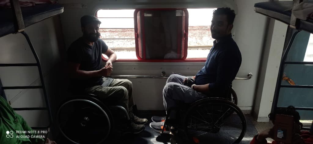 Mohammad Imran and fellow wheelchair traveler inside an Indian Railways train compartment by the window